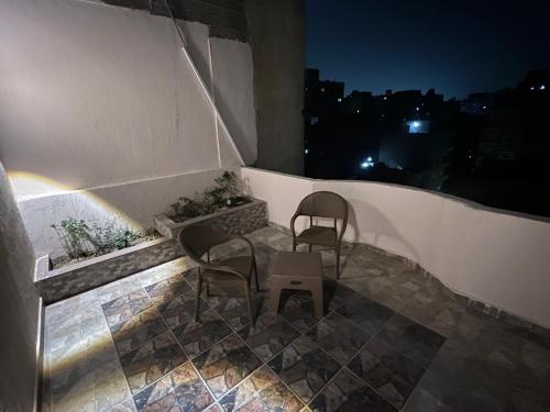 two chairs and a table on a balcony at night at NEAR THE PYRAMIDS in Cairo