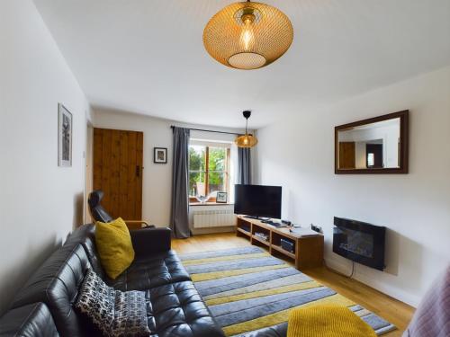 a living room with a leather couch and a television at Cosy Stone Cottage in Llanarthney nr Carmarthen in Llanarthney