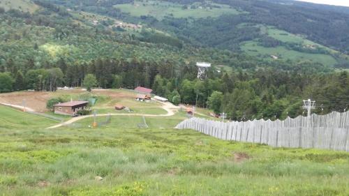 une colline avec une maison et une clôture dans un champ dans l'établissement chalet le pastoral, à Saint-Anthème
