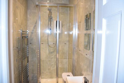 a shower with a glass door in a bathroom at Three Bedroom House Lancaster Road in London