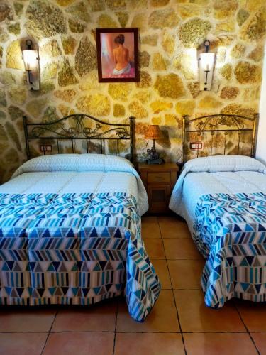 two beds in a room with a stone wall at El Ventorrillo Grande in Riópar