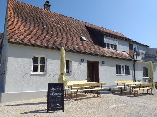 un bâtiment avec des tables et des parasols devant lui dans l'établissement Landcafe SIMA & Zimmervermietung, à Forheim