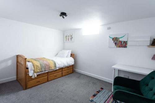 a small bedroom with a bed and a green chair at 2/3 Bed House in the centre of Northampton in Northampton