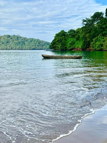 a boat sitting on the water next to a beach at Valdivia Homes -Príncipe in Santo António