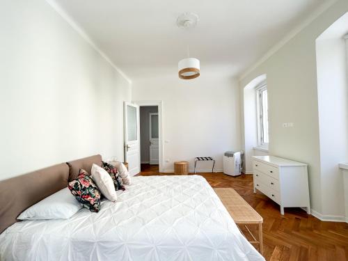 um quarto branco com uma cama grande e almofadas em MAISON NOEL em Trieste