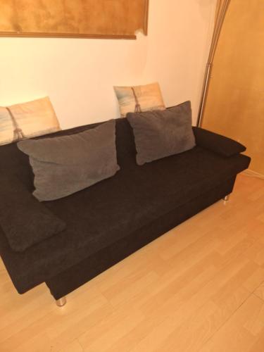 a black couch with pillows on it in a room at Privatunterkunft, Ferienwohnung, Monteurswohnung in Bottrop