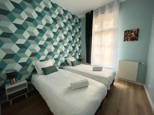 two beds in a room with a checkered wall at Central Park in Serris