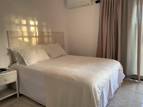 uma cama com lençóis brancos e almofadas num quarto em Itacaré Flats em Itacaré