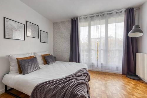 1 dormitorio con cama y ventana grande en L'industriel - 2'mn du métro - aux portes de Paris, en Saint-Mandé