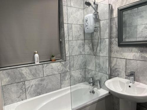 een badkamer met een bad en een wastafel bij Isinmi Home - Close to MCR City in Manchester