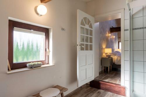 une salle de bains avec une porte et une fenêtre ainsi qu'une chambre dans l'établissement La Bergerie, à Leuze-en-Hainaut