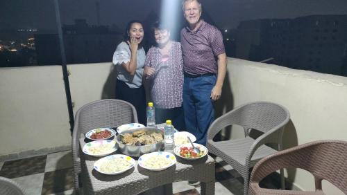 a group of people standing on a balcony with a table with food at Jessy Pyramids View Inn in Cairo