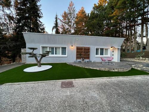 una pequeña casa blanca con un árbol en el patio en L’Appar(T) du Grand Bois - Jacuzzi -, en Soucelles