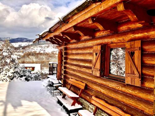 a log cabin in the snow with benches and a window at Dom z Widokiem in Piwniczna