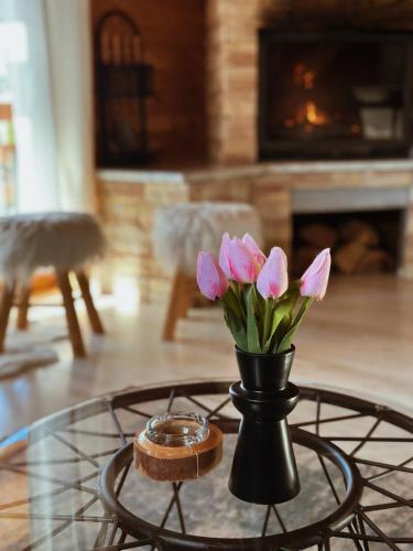 a vase with pink flowers on a glass table at Casa Mia Resort in Kupres
