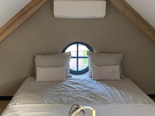 1 cama con 2 almohadas en una habitación con ventana en De Slaapsoof en Lier