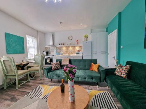 a living room with a green couch and a table at Eclectic 1BD in the Heart of Cheltenham! in Cheltenham