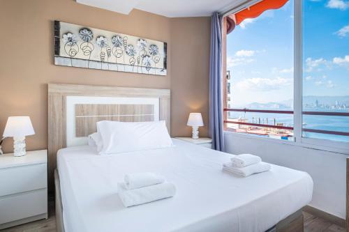 a bedroom with a white bed and a large window at Don Miguel 4-F Apartment Levante Beach in Benidorm