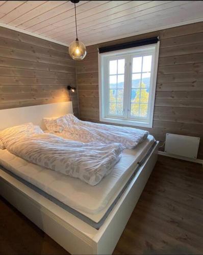 a large bed in a room with a window at Koselig, nyere hytte til leie in Stranda