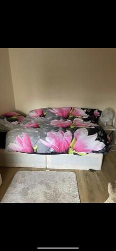 a bed with pink flowers on it in a bedroom at Beautiful Studio flat in Enfield Lock