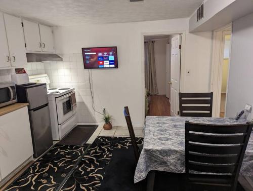 a kitchen with a table and a television on the wall at Cozy basement apartment in the heart of Oakville in Oakville