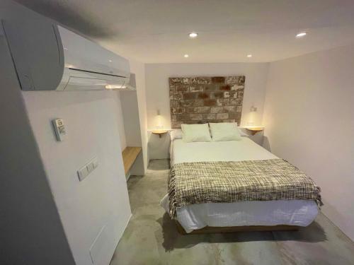 a bedroom with a bed and a brick wall at CASA MÚA in Frigiliana