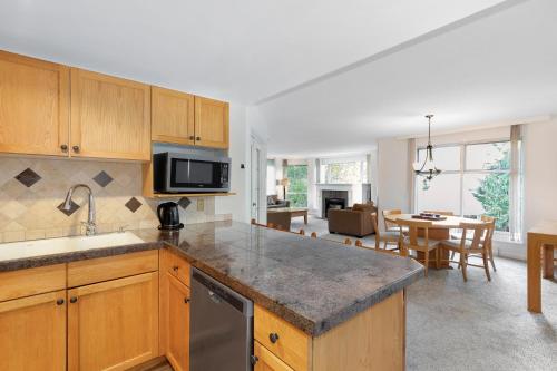 a kitchen with wooden cabinets and a dining room at The Woodrun Lodge by Whiski Jack in Whistler