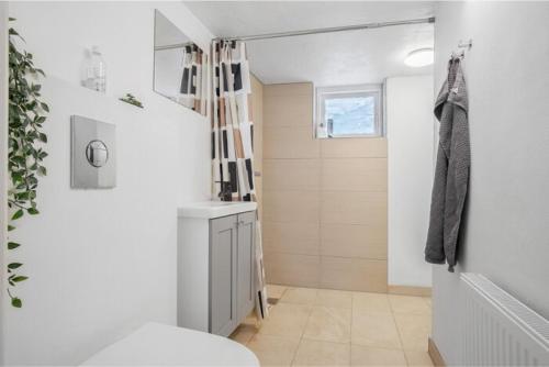 a white bathroom with a toilet and a sink at Cosy private room in Slagelse