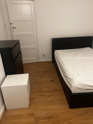 a bedroom with a bed and a dresser and a door at Spontaneous apartment in Kingston upon Thames