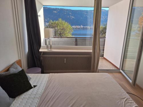 a bedroom with a bed and a large window at Seeapartment am Ossiacher See am Fuße der Gerlitzen in Stiegl