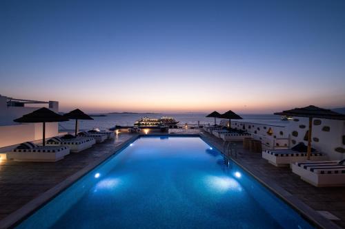 a swimming pool with a view of the ocean at sunset at Hotel Tagoo in Mýkonos City