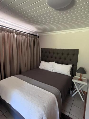 a bedroom with a large bed with a gray headboard at Hogsback Misty Oaks Cottage in Hogsback