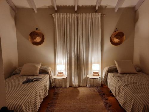 a bedroom with two beds and two tables with lamps at Casa La Buena Ola in Playa del Hombre