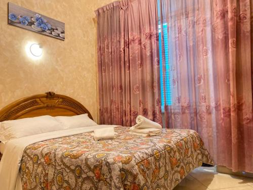 a bedroom with a bed and a curtain with towels on it at Roma Guest House in Rome