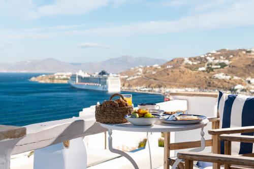 - une table avec de la nourriture sur le balcon donnant sur l'océan dans l'établissement Hotel Tagoo, à Mykonos
