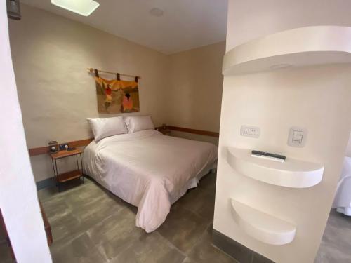a small bedroom with a bed and a refrigerator at Posada del Musiquero in Cafayate