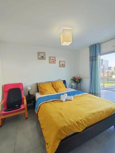 une chambre avec un grand lit et une chaise rouge dans l'établissement JENNY GÎTE - HOMESTAY, à Plancoët