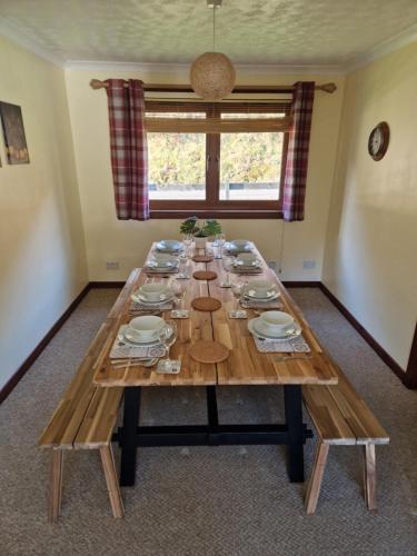 une grande table en bois avec des assiettes et de la vaisselle dans l'établissement Wilmar Lodge, à Arrochar