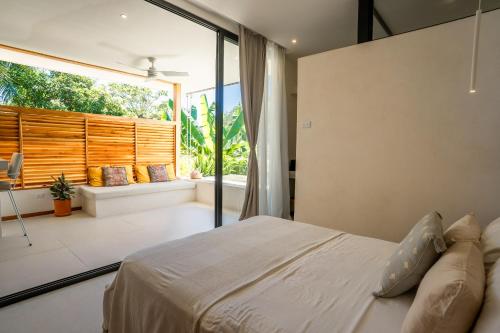 a bedroom with a bed and a large window at Botanika Suites in Santa Teresa Beach
