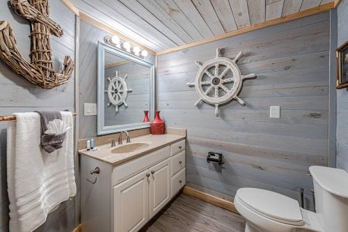 a bathroom with a sink and a toilet and a wheel on the wall at Captain's Quarters at Island Breeze of CB in Carolina Beach