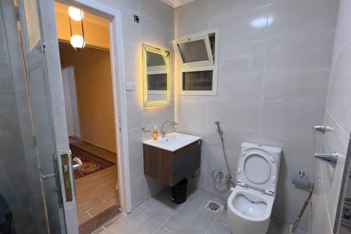 uma casa de banho com um WC branco e um lavatório. em Modern and cozy apartment no Cairo