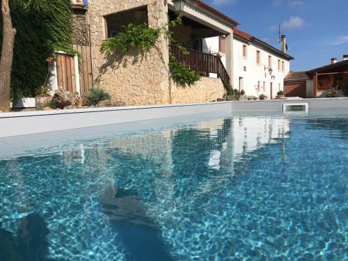 a swimming pool with blue water in front of a house at ACOLINA in Aguda