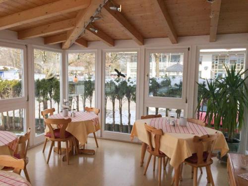 un comedor con mesas, sillas y ventanas en Pension am See en Wörthsee