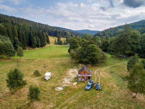 an aerial view of a cabin in a field with cars at Drewniany domek pod masywem Śnieżnika in Nowa Morawa