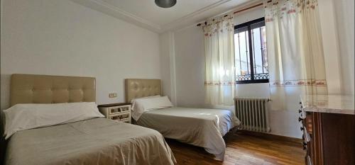 una camera da letto con due letti e una finestra di Apartamentos GARDEN a Salamanca