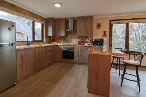 una cocina con armarios de madera y una barra con taburetes en mirabosque new aparments 4, en Osorno
