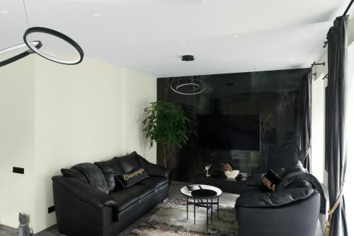 una sala de estar con 2 sofás de cuero negro en Koralas en Klaipėda