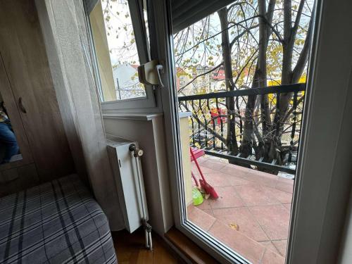 una puerta que da a un balcón con vistas a un árbol en Apartman Mir, en Novi Sad