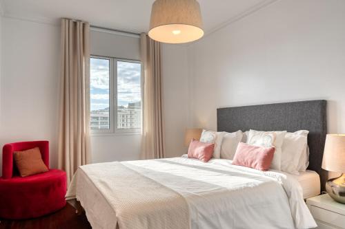 フンシャルにあるEncarnacao Apartment, a Home in Madeiraのベッドルーム1室(大型ベッド1台、赤い椅子付)