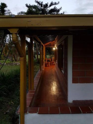 a covered porch of a house with tables and chairs at Beautiful Country - Ser feliz - House located in Llanogrande in Rionegro
